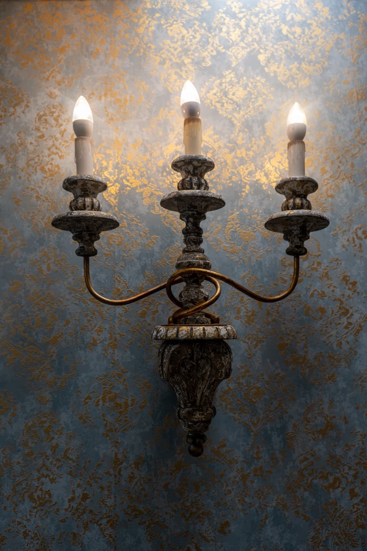 Gold candle sconce against the blue-and-gold wall at LNO Boutique day spa in Centennial, CO